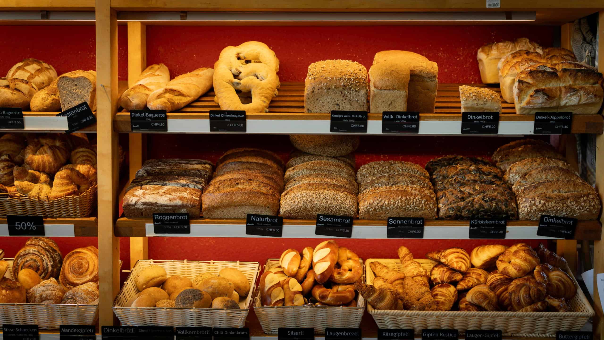 Holzregal mit diversen Backfermentbroten, Brötchen und Süssgebäck