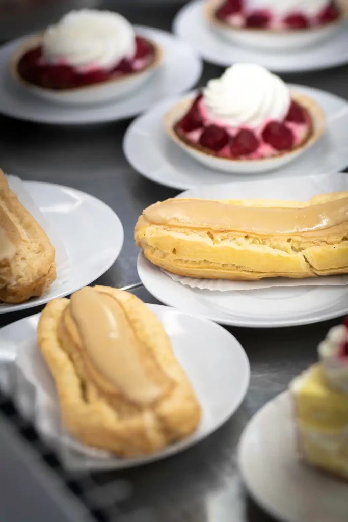 Vital Speisehaus Karamell Éclaire und Himbeertörtchen auf Tellern